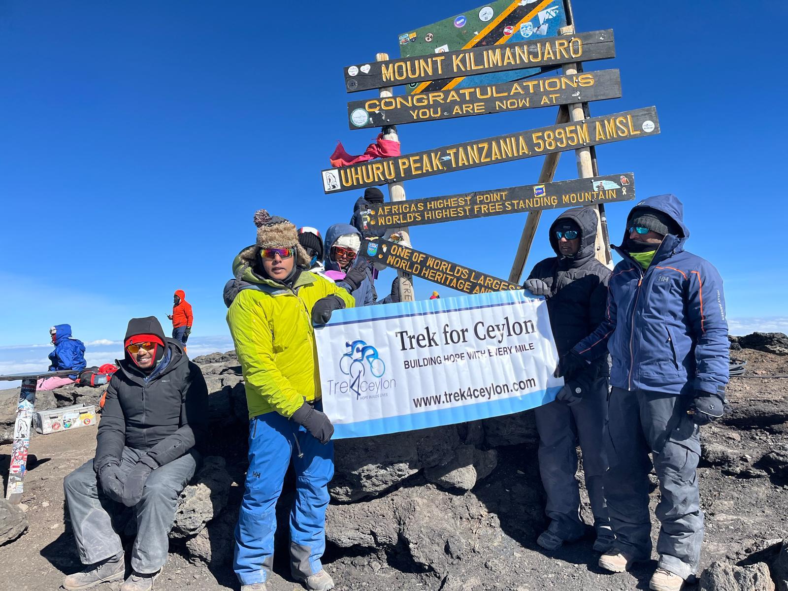 Hikers at the top of Mt Kilimanjaro holding a Trek4Ceylon banner